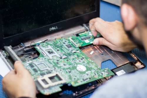 A person removing a circuit from a Dell laptop