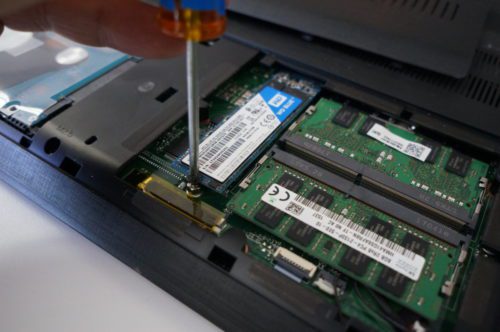 A laptop's back is being worked on with a screwdriver